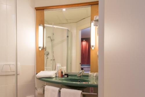a bathroom with a green sink and a mirror at Ibis Madrid Fuenlabrada in Fuenlabrada