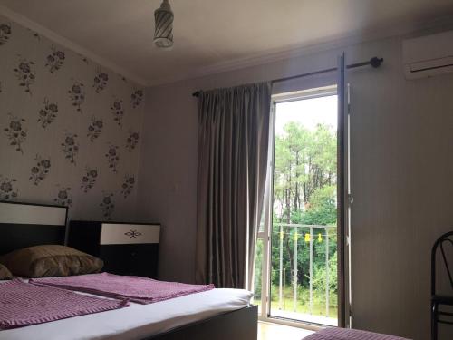 a bedroom with a bed and a large window at Private Cottage at the Black sea in Shekvetili
