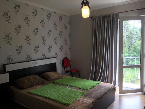 a bedroom with a bed with a green comforter and a window at Private Cottage at the Black sea in Shekvetili
