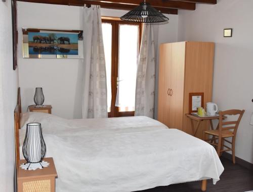 a bedroom with a white bed and a window at La Bardelière in Corbelin
