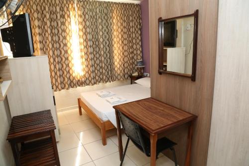a small room with a bed and a mirror at Royal Plaza Hotel in Apucarana