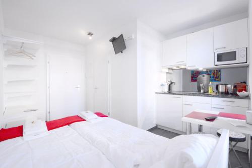 a white room with a bed and a kitchen at HITrental Station Apartments in Lucerne