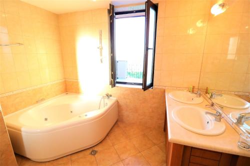 a bathroom with two sinks and a tub and a window at Kaliakria Sea View Apartments in Topola