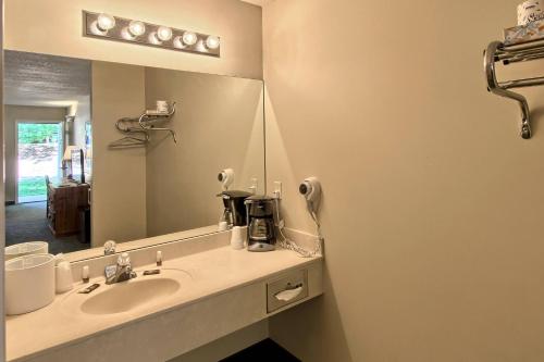 een badkamer met een wastafel en een grote spiegel bij The Legend Cottage Inn in Bellaire
