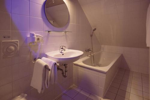 a bathroom with a sink and a tub and a mirror at Central Hotel bel étage in Hamburg