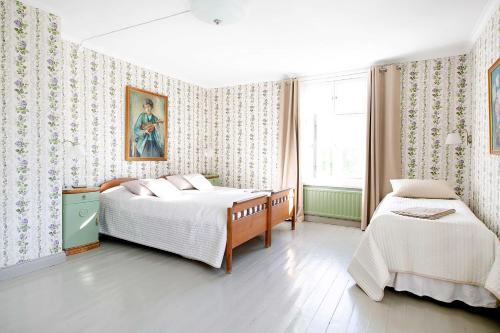 a bedroom with two beds and a painting on the wall at Tammiston Bed&Breakfast in Naantali