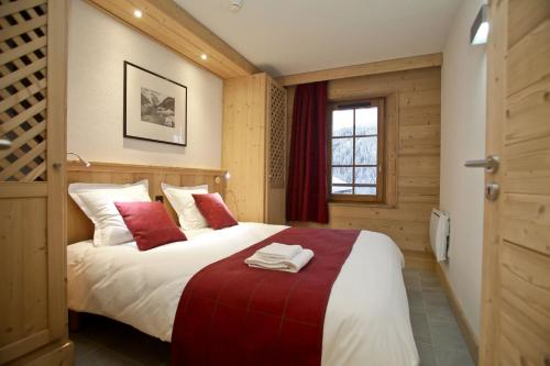 a bedroom with a large white bed with red pillows at Résidence Prestige Odalys Les Fermes de Châtel in Châtel