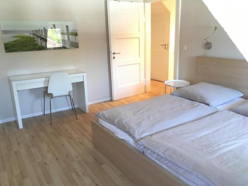 a white bedroom with a bed and a desk at Apartments Thommen Lohengrinstr in Nuremberg