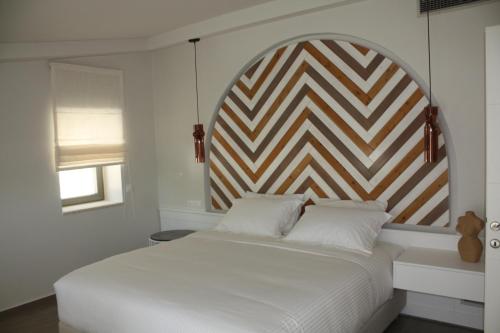 a bedroom with a white bed with a geometric headboard at Anemolia Parga Suites in Sarakiniko