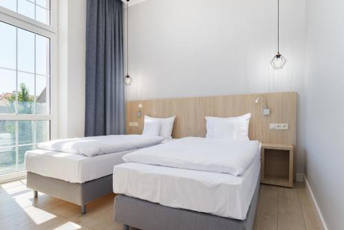 2 łóżka w pokoju hotelowym z oknem w obiekcie Apart Avenue 22 w Poznaniu
