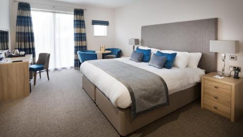 a bedroom with a large bed with blue pillows at Dale Hill Hotel in Ticehurst