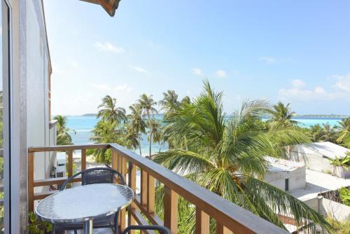 a balcony overlooking a beach with palm trees at Ocean Retreat and Spa in Guraidhoo