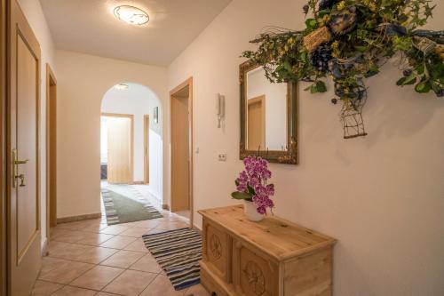 a hallway with a table and a mirror and flowers at Ferienhaus Regina in Tux