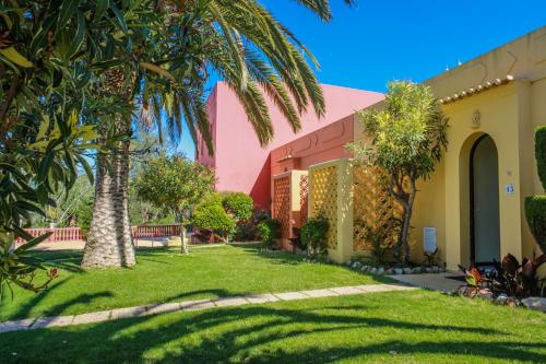 a pink house with a palm tree in the yard at Colina Village in Carvoeiro