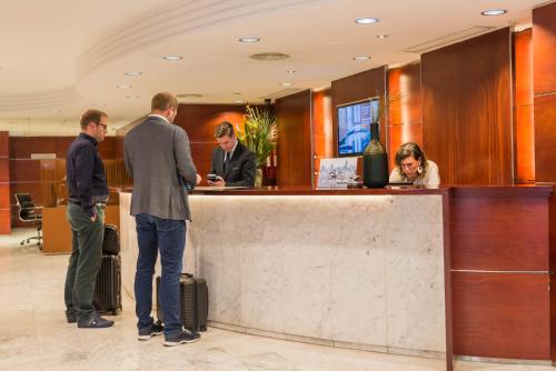 a group of people standing at a counter in a lobby at Aparthotel Mariano Cubi Barcelona in Barcelona