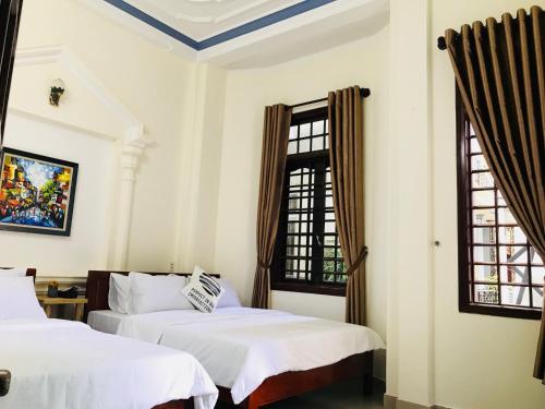 two beds in a room with two windows at Eva Homestay in Hue