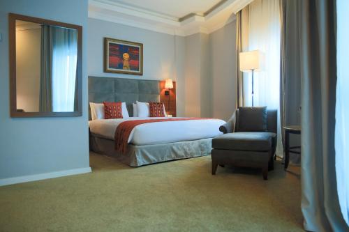 a bedroom with a bed and a chair and a mirror at Swiss Inn Nexus Hotel in Addis Ababa