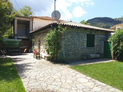 a small stone house with a patio and a yard at Villa Frias in Asprogerakata