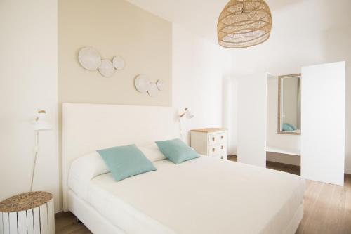 biała sypialnia z białym łóżkiem z niebieskimi poduszkami w obiekcie Apulianstay-Sabbia w mieście Monopoli
