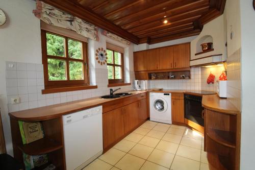 a kitchen with wooden cabinets and a washer and dryer at Haus Franz by ISA AGENTUR in Bad Kleinkirchheim