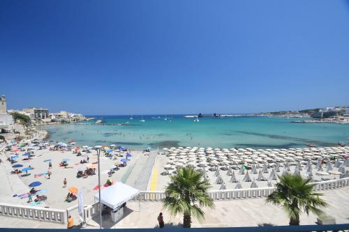 a beach with umbrellas and people in the water at B&B PALAZZO MARZO in Otranto
