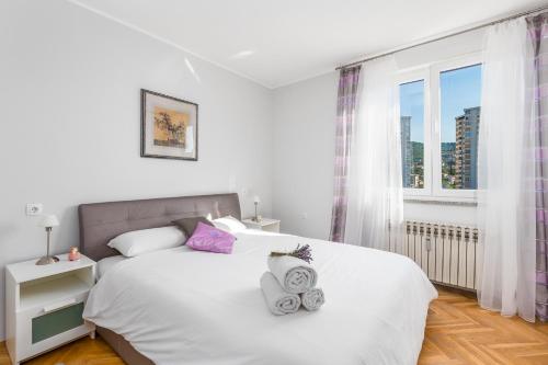 1 dormitorio con 1 cama blanca y 2 toallas en Apartment City View Rijeka, en Rijeka
