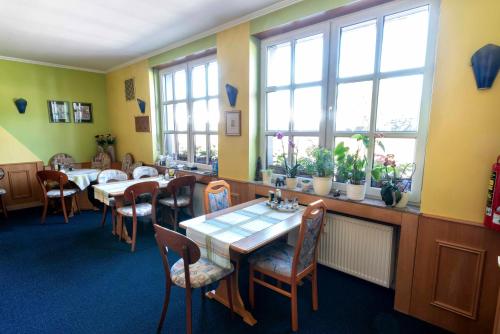 a dining room with tables and chairs and windows at City Hotel Hilden in Hilden