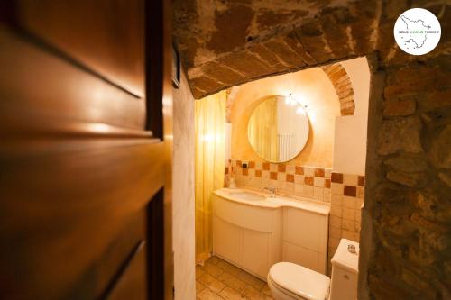 y baño con lavabo, aseo y espejo. en Casa Scuderia en Volterra
