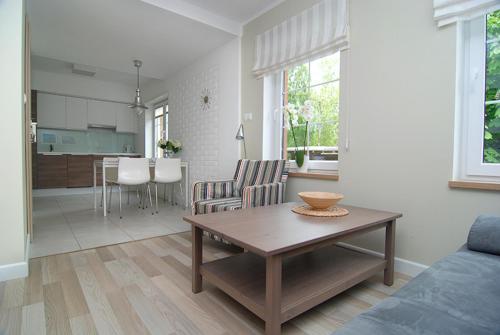 a living room with a table and a kitchen at Apartament Plaza in Rowy