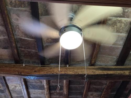 a ceiling fan in a room with a brick wall at Casa SoleLuna in Calcata