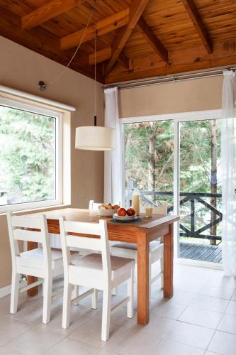 a dining room with a wooden table and white chairs at Plenilunio Mar de las Pampas in Mar de las Pampas