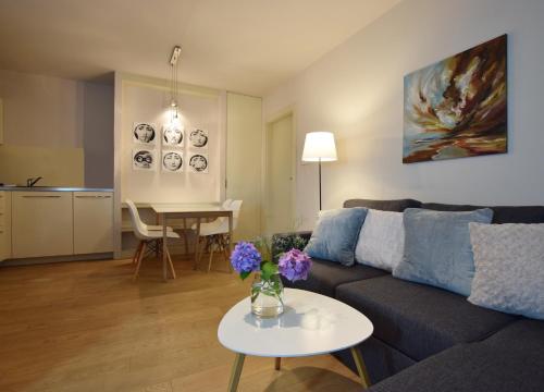 a living room with a couch and a table with flowers on it at Piłsudskiego In City Apartments in Krakow