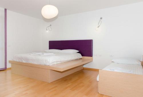 a bedroom with two beds and a purple headboard at Hotel Pramaggiore in Forni di Sotto