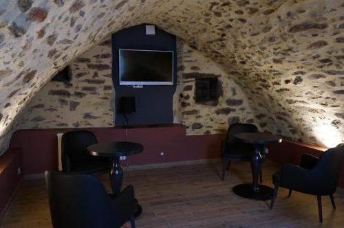 een kamer met tafels en stoelen en een tv in een grot bij Hôtel Saint-Roch, The Originals Relais in Saint-Ybard