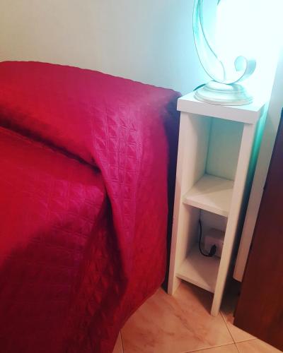a bed with a red blanket and a table with a lamp at B&B 500 Miglia  in Tempio Pausania