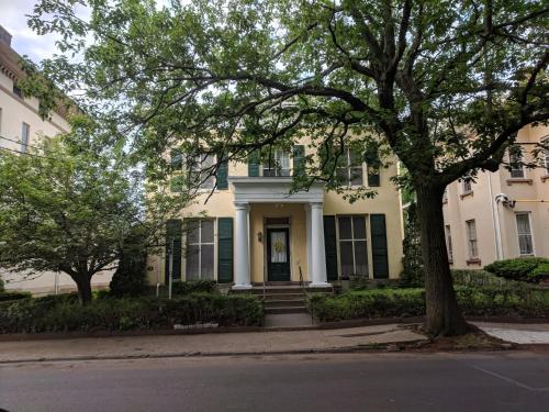 ein weißes Haus mit grünen Rollläden und einem Baum in der Unterkunft The Historic Mansion in New Haven
