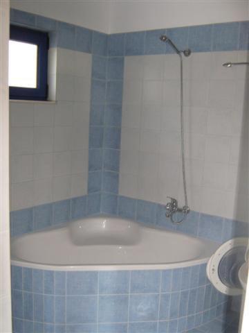 a blue tiled bathroom with a tub and a window at Studios Fokies in Hora Sfakion