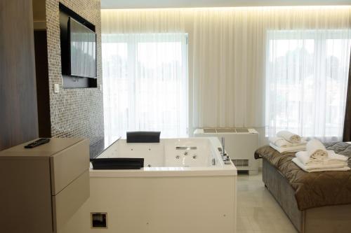a bathroom with a bath tub and a couch at Princ Apartment in Niš