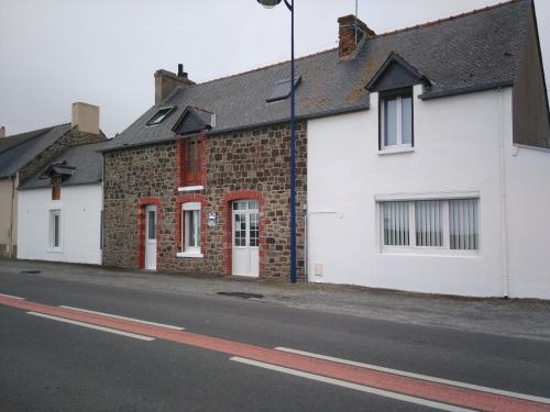 una fila di case bianche sul lato di una strada di Les Greniers De Blanche a Le Vivier-sur-Mer