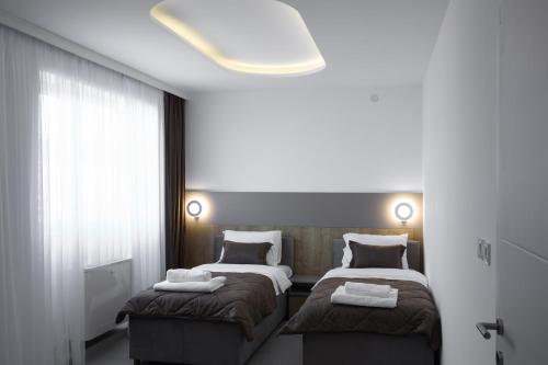 a bedroom with two beds and a large window at Princ Apartment in Niš