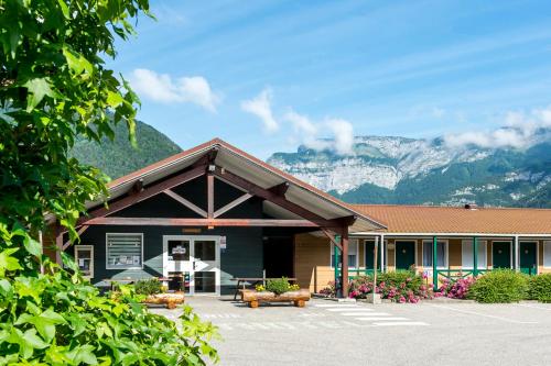 a building with mountains in the background at Fasthotel Thones in Thônes