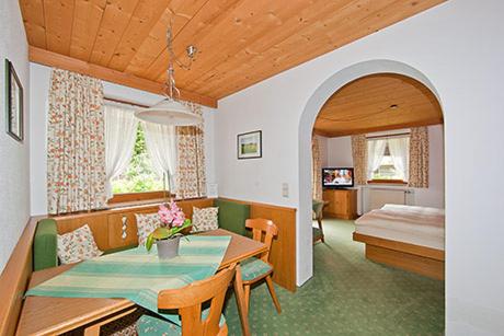 ein Wohnzimmer mit einem Tisch und ein Schlafzimmer in der Unterkunft Alpenhof Klais in Klais