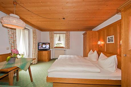 a bedroom with a large bed and a table at Alpenhof Klais in Klais