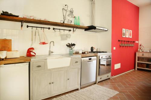 a kitchen with white cabinets and a red wall at Agriturismo Biomatto in Arona