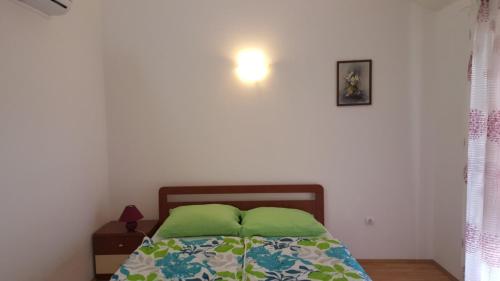 a bedroom with a bed with two green pillows at apartmani Vesna in Pinezici