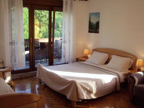 a bedroom with a bed and a large window at PLITVICE KONAK Daic in Plitvička Jezera