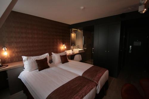 a hotel room with a large bed and a bathroom at Amosa Liège City Centre Hotel in Liège