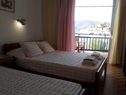 a bedroom with two beds and a window with a balcony at Bissias Guest House in Galatas