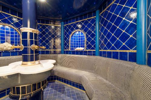 ein blau gefliestes Bad mit einem Waschbecken und einer Badewanne in der Unterkunft Chalet Silvretta Hotel & Spa in Samnaun