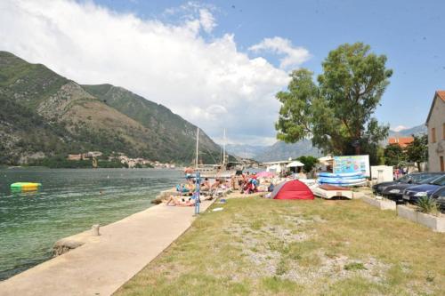 a group of people sitting on the shore of a lake at Apartments Olive in Kotor